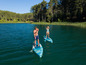 Dwie osoby pływają na paddleboardach po jeziorze.