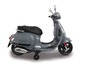Elektryczny skuter Vespa dla dzieci w kolorze szarym z kółkami podporowymi.