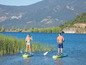 Dwie osoby na paddleboardach, wiosłują po jeziorze.