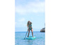 Kobieta wiosłuje na pompowanym paddleboardzie w turkusowej wodzie.