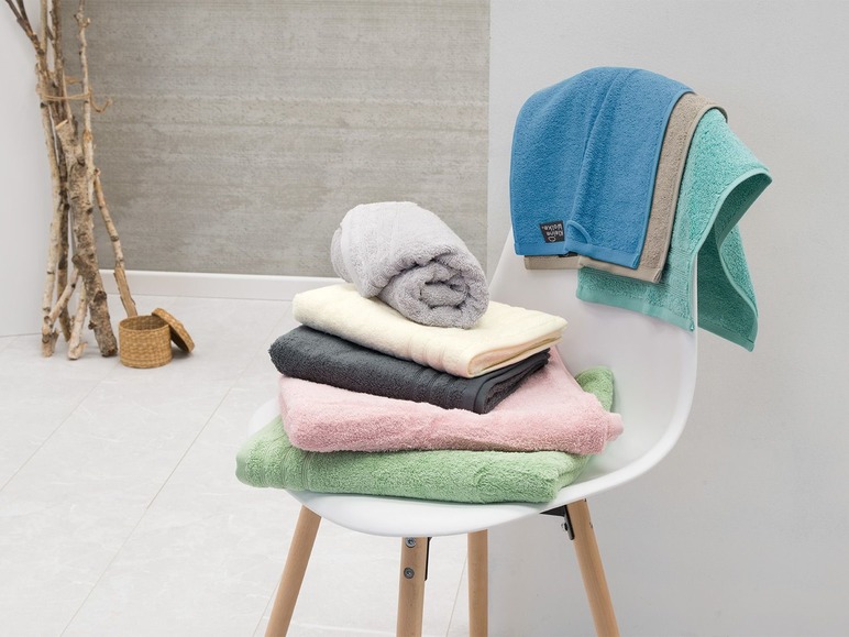 Stosik ręczników kąpielowych i ręczników, w tym niebieski ręcznik marki 'Kleine Wolke'.