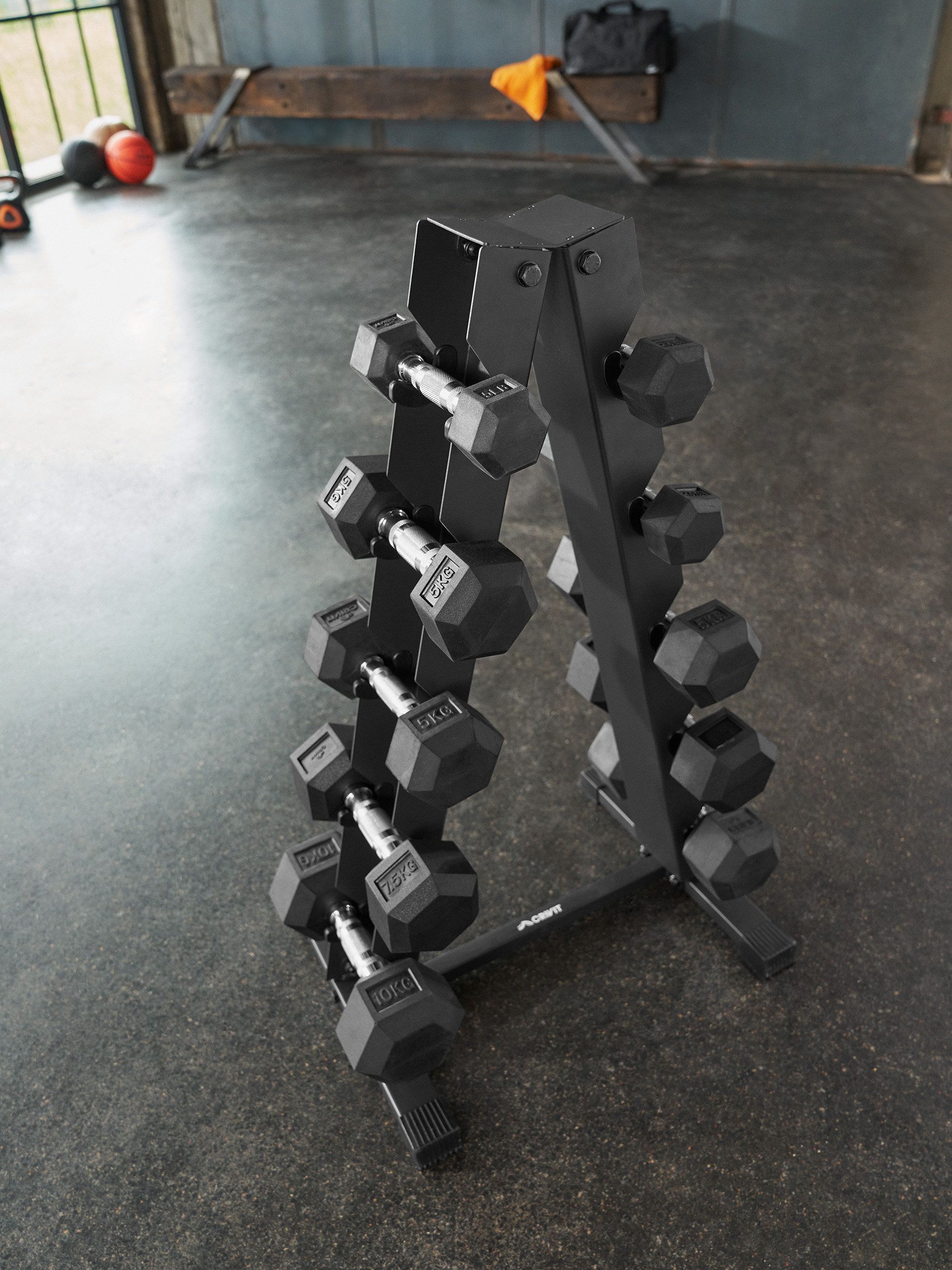 Czarny stojak na hantle, wypełniony hantlami o różnej wadze, na siłowni.