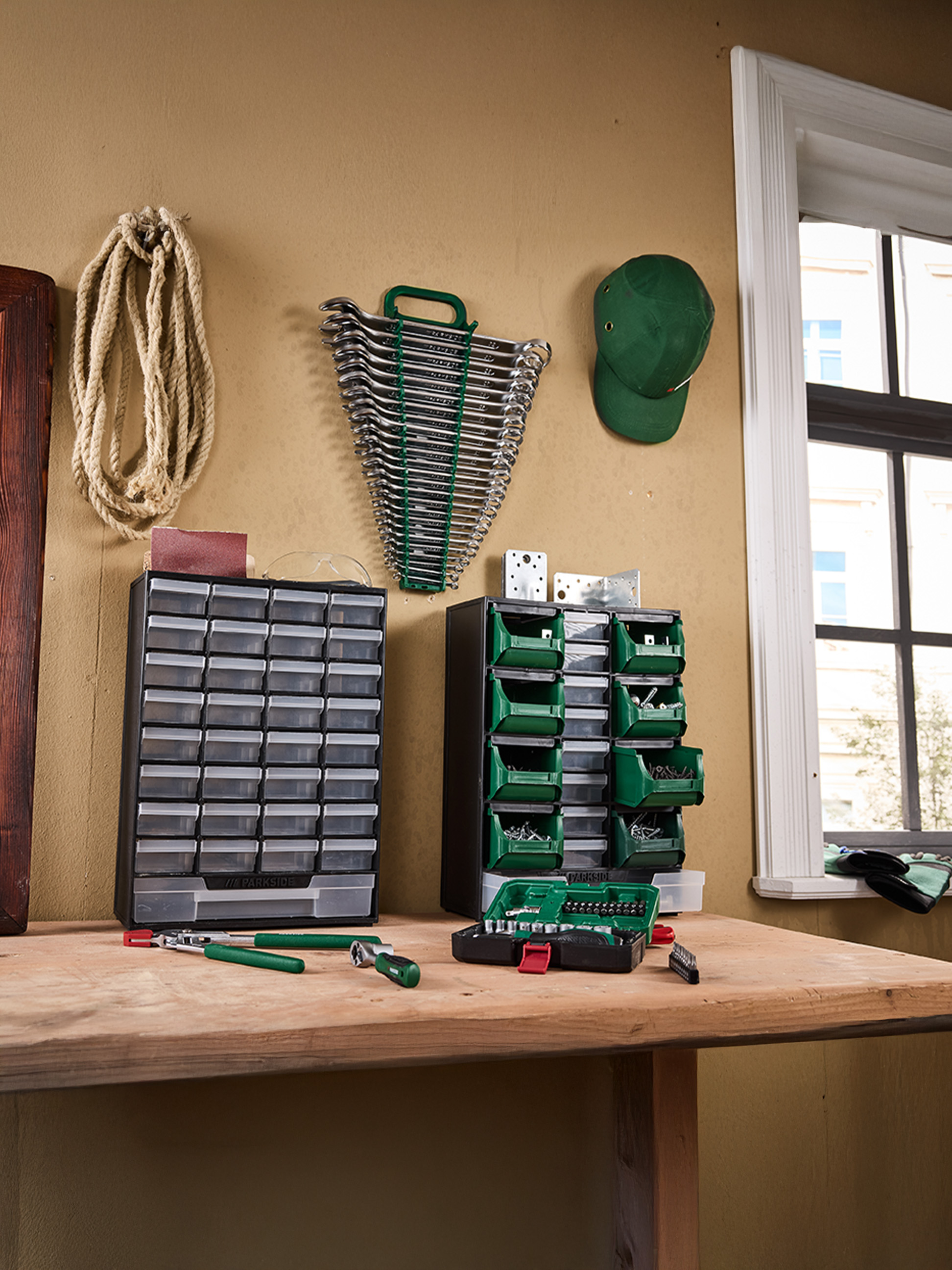 Narzędzia i organizery PARKside na stole warsztatowym, w tym klucze, śruby i bity.