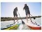 Dwie osoby uprawiające paddleboarding na dmuchanych deskach Crivit.