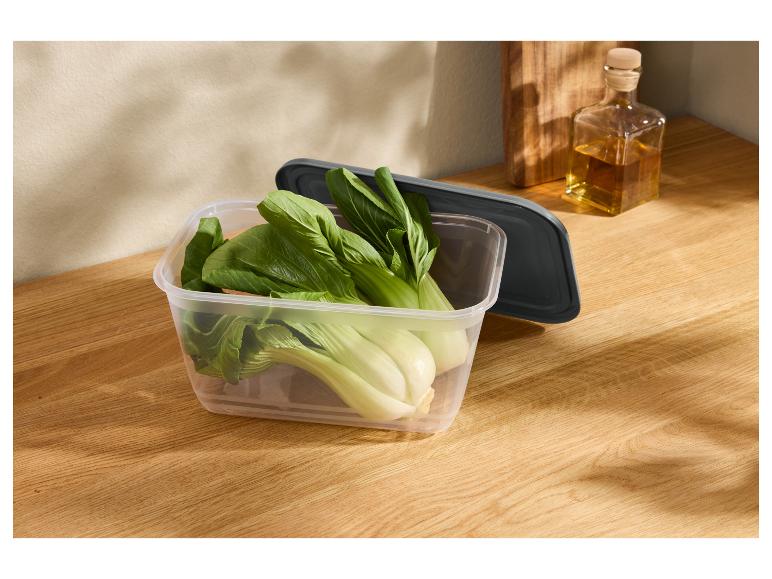 Świeże pak choi w przezroczystym pojemniku na drewnianym blacie.