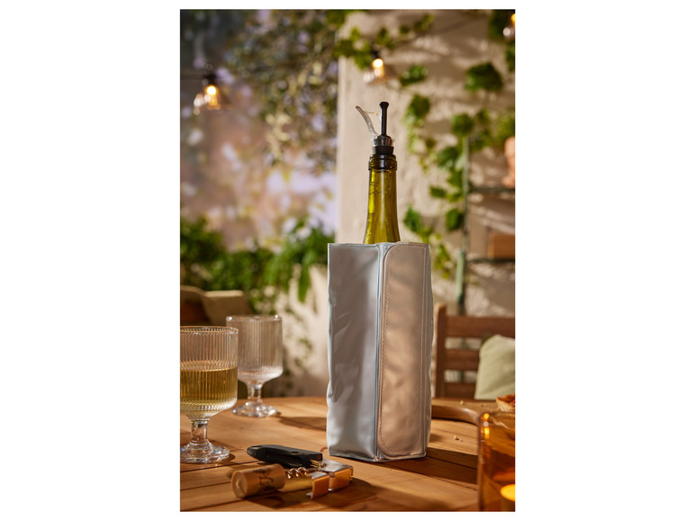 Butelka białego wina w torbie chłodzącej, dwie szklanki i otwieracz do wina na drewnianym stole.