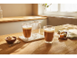 Dwa szklanki latte i ciastka na drewnianym stole.