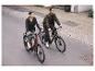 Dwie osoby jadą na rowerach po miejskiej drodze na dwóch rowerach elektrycznych.