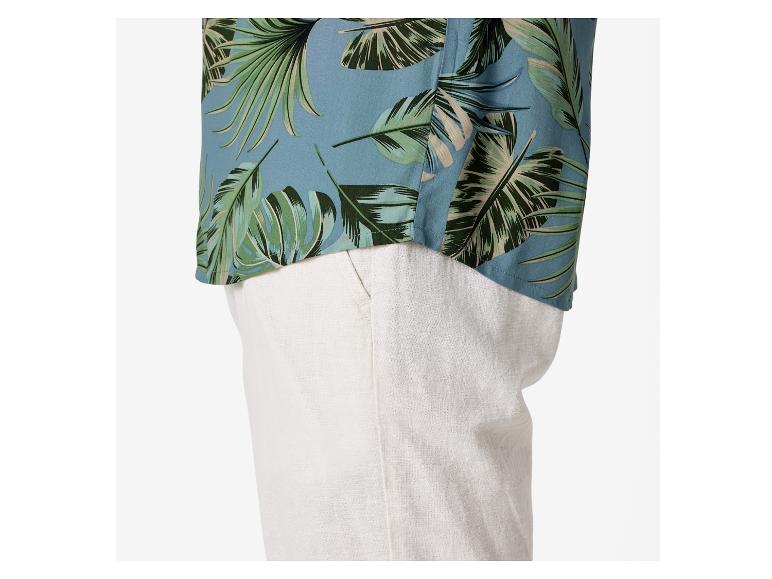 Koszula z tropikalnym wzorem i beżowe spodnie lniane.