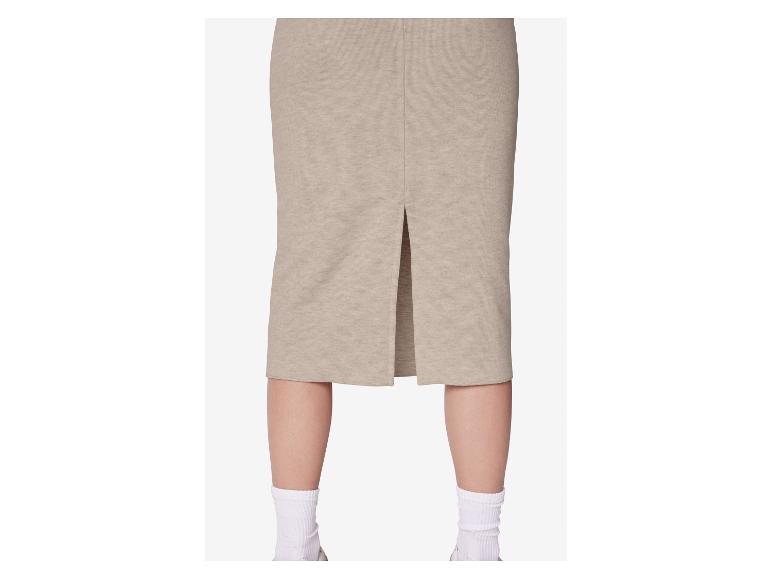 Beżowa spódnica midi z rozcięciem z tyłu, noszona przez osobę w białych skarpetkach i sneakersach.
