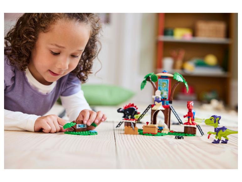 Dziewczynka bawi się zestawem LEGO DUPLO domek na drzewie i figurkami dinozaurów.