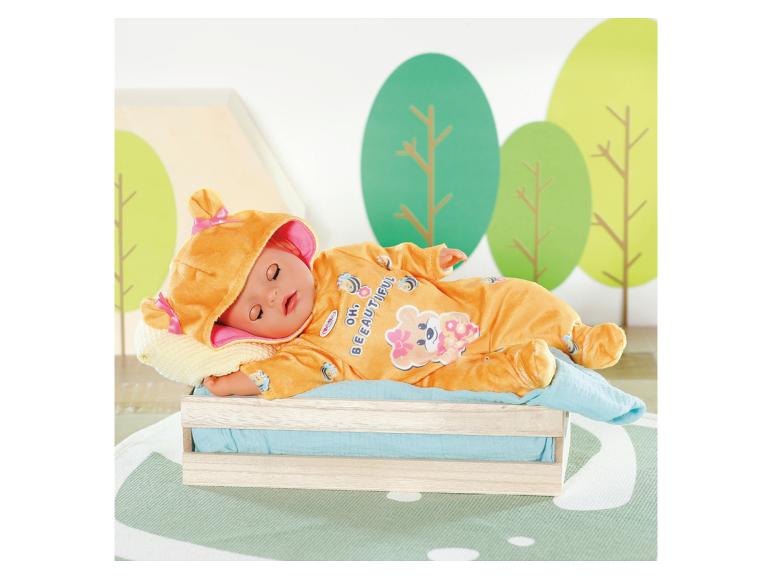 Lalka BABY born w pomarańczowym śpioszku w pszczółki, śpiąca w drewnianym łóżeczku.