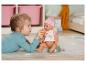 Dziewczynka karmi lalkę Baby Born z butelki.