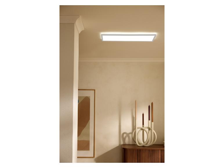Prostokątna lampa sufitowa oświetla pokój ze świecznikiem i oprawionym obrazem.