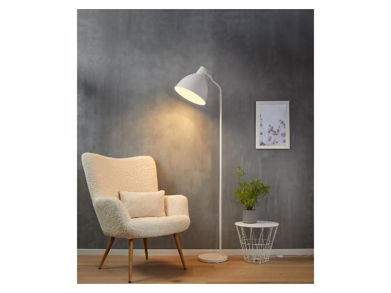 Biała lampa stojąca z fotelem, rośliną i stolikiem kawowym.