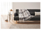 Szara sofa z pled z kratą i dywanem.