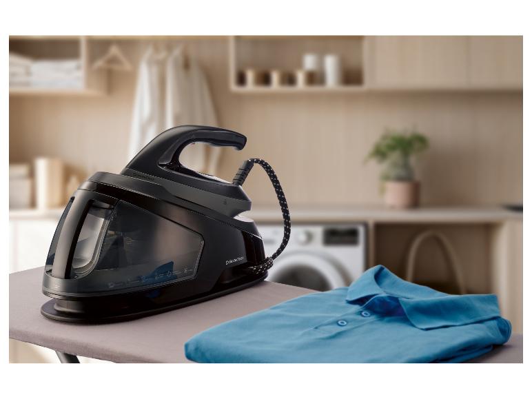 Stacja parowa na desce do prasowania ze złożoną niebieską koszulą.