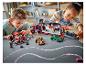 Dwoje dzieci bawi się zestawami LEGO Speed Champions, w tym ciężarówką transportową i samochodami wyścigowymi.