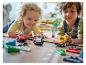Dwoje dzieci bawi się samochodami wyścigowymi LEGO Duplo na podłodze.