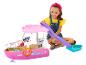 Uśmiechnięta dziewczynka bawi się różową łodzią-zabawką Barbie, ze zjeżdżalnią i akcesoriami.
