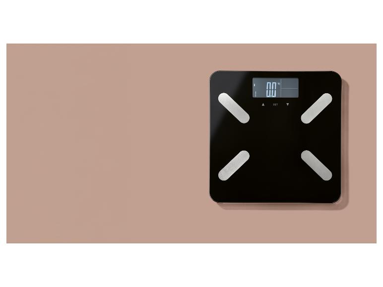 Czarna waga cyfrowa z wyświetlaczem pokazującym „0.0 kg”, umieszczona na różowej powierzchni.