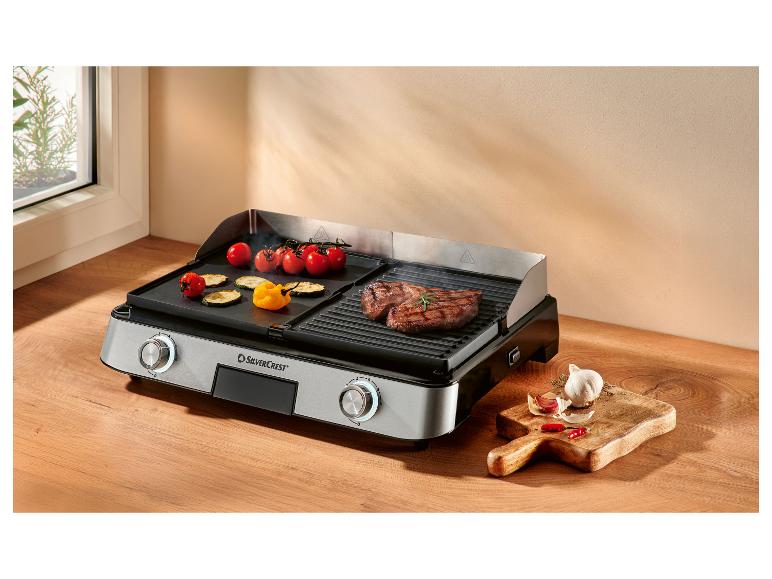 Grill elektryczny z grillowanym mięsem i warzywami, z czosnkiem i papryczkami chili z boku.