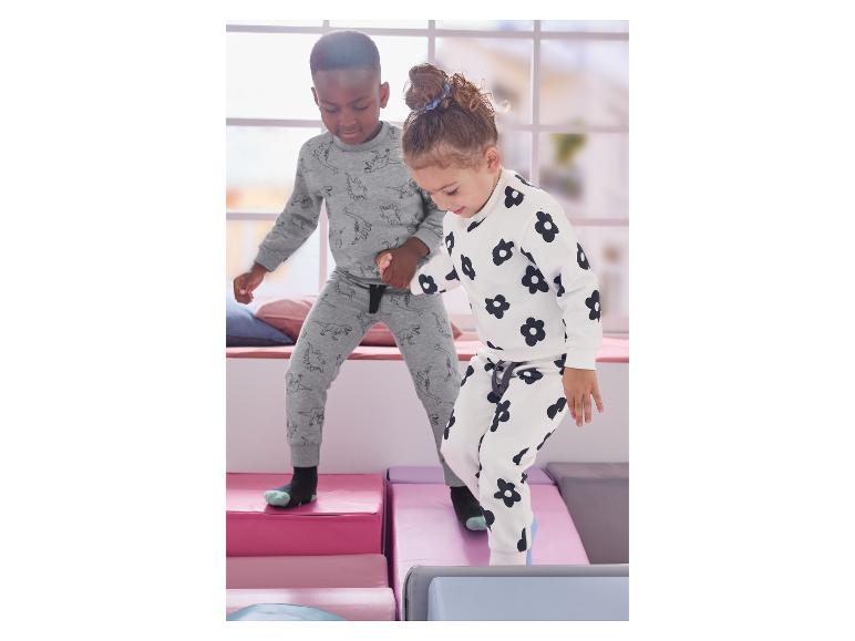 Dwoje dzieci bawi się na miękkich klockach, ubranych w piżamy we wzory.