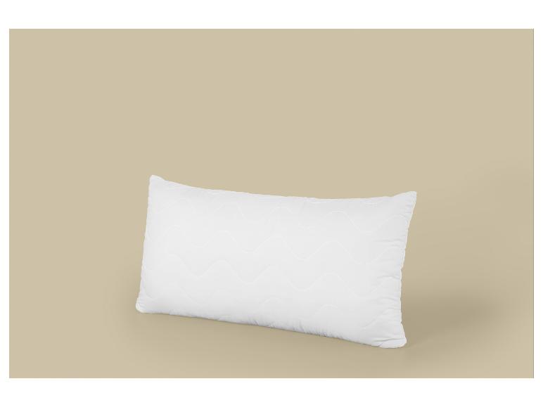 Biała prostokątna poduszka z falistym wzorem na beżowym tle