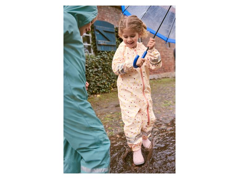 Dziecko w płaszczu przeciwdeszczowym skacze po kałużach.
