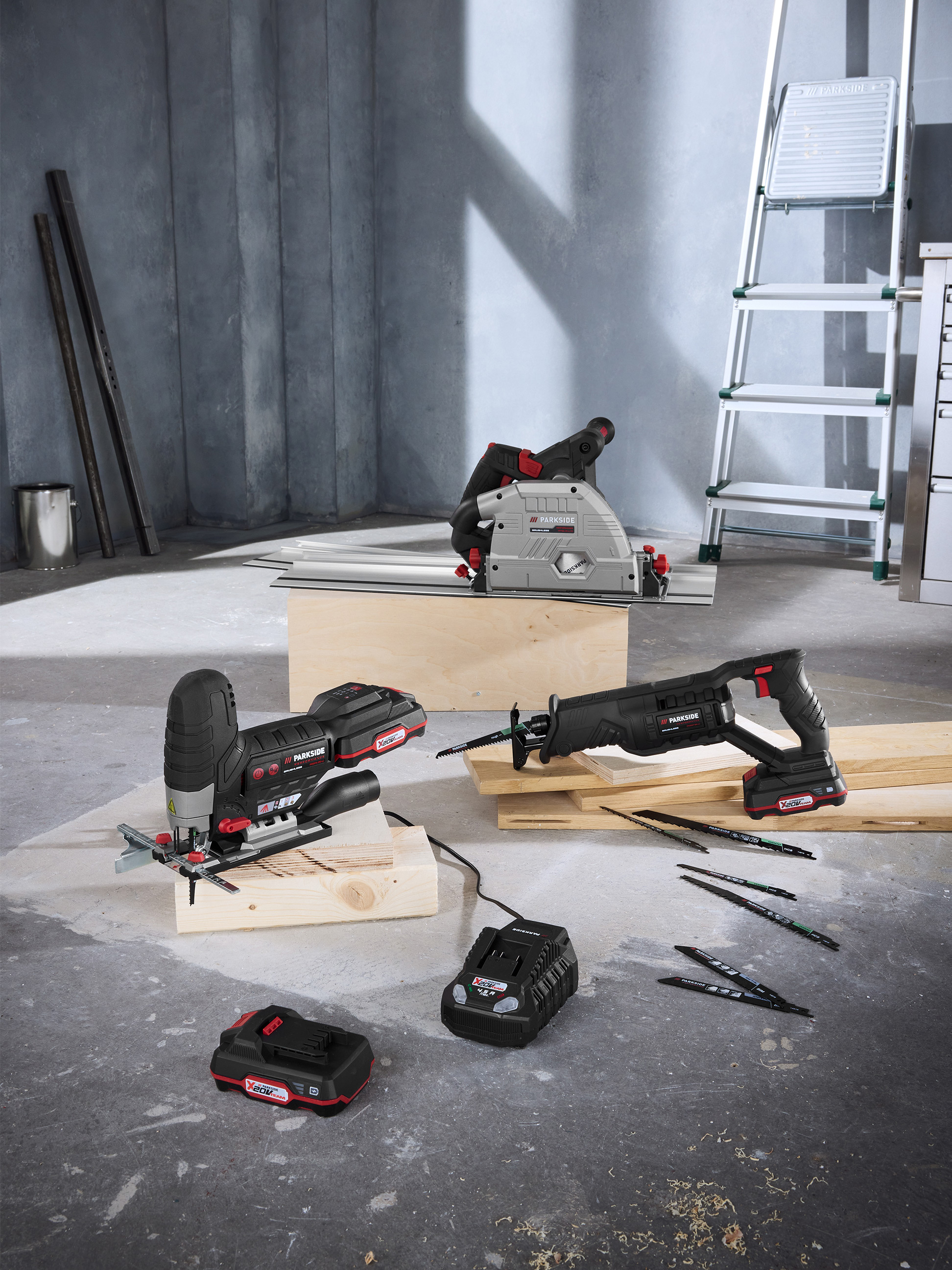 Elektronarzędzia Parkside: pilarka tarczowa, wyrzynarka i piła szablasta z akumulatorami i akcesoriami w warsztacie.