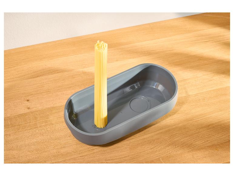 Szary dozownik do makaronu z surowym spaghetti na drewnianym stole.