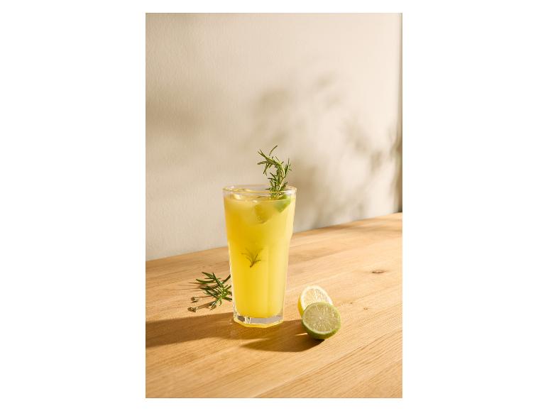 Szklanka lemoniady z rozmarynem i limonką na drewnianym stole.