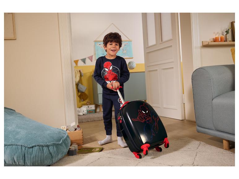 Chłopiec w piżamie Spiderman ciągnie dziecięcą walizkę Spiderman w pokoju.
