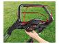 Zbliżenie dłoni wkładającej baterię do uchwytu kosiarki.