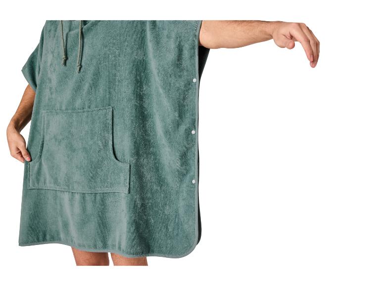 Zielone ponczo ręcznikowe z kapturem i kieszenią, z wyciągniętą ręką
