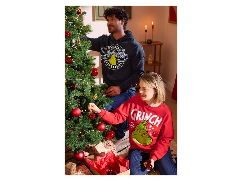 Para dekoruje choinkę w bluzach z motywem Grincha.