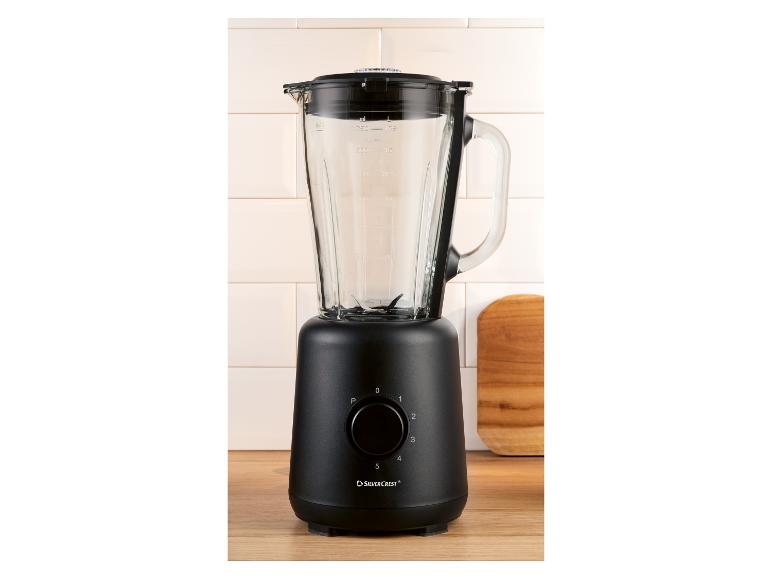Czarny blender ze szklanym dzbankiem, pokrętłem sterującym i oznaczeniami miar na drewnianej powierzchni.
