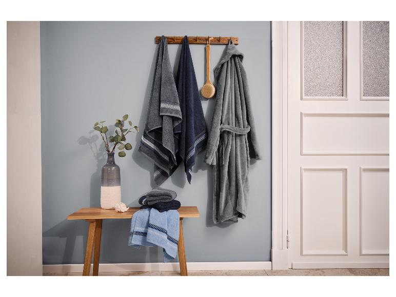 Łazienka z ręcznikami, szlafrokiem i drewnianą ławką z wazonem i muszlą.