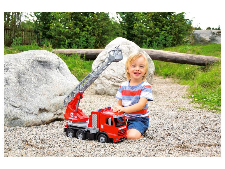 Dziecko bawi się czerwonym wozem strażackim z drabiną.