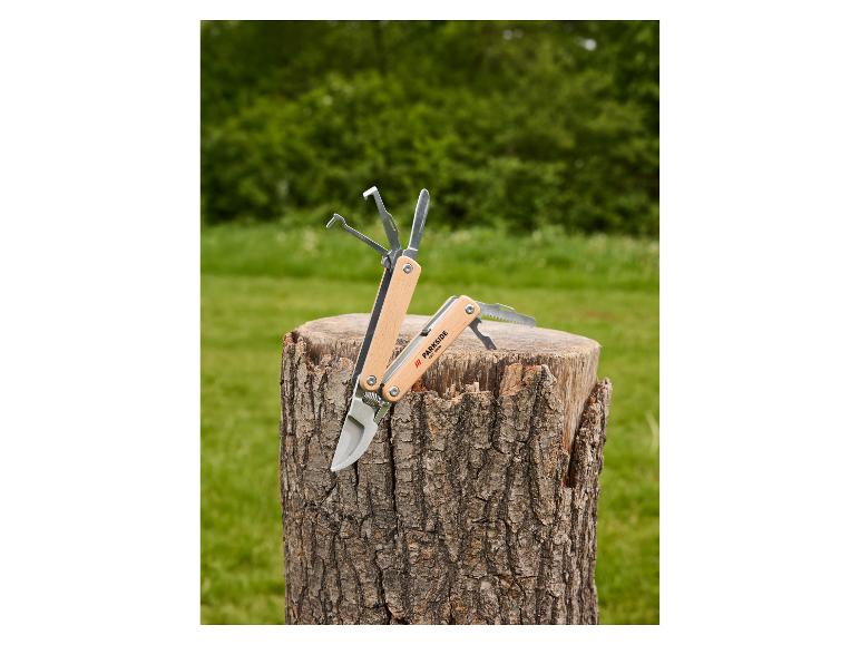 Multitool z drewnianą rączką i różnymi narzędziami na pniu drzewa.