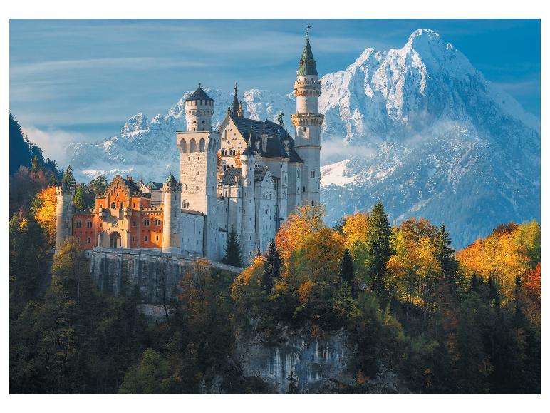 Zamek Neuschwanstein, otoczony jesiennymi drzewami i ośnieżonymi górami.
