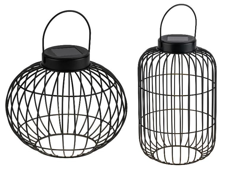 Dwie czarne metalowe dekoracyjne latarnie solarne, jedna kulista i jedna cylindryczna.