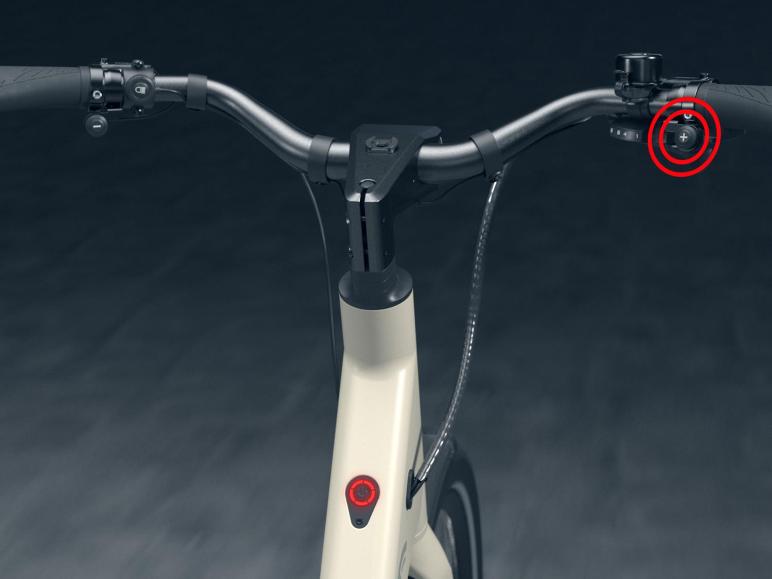 Kierownica białego roweru elektrycznego z elementami sterującymi.