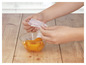Ręka nakładająca silikonową nakładkę na miskę z brzoskwiniami.