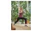 Kobieta w czarnych spodniach i fioletowej koszulce, ćwicząca z piłką fitness.