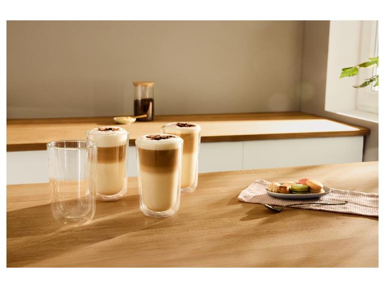Trzy szklanki kawy latte z pianką i wiórkami czekolady, obok makaroników i ciastek.