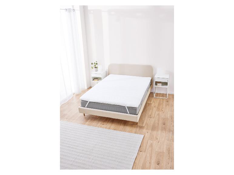 Biała ochrona materaca na łóżku w minimalistycznej sypialni.