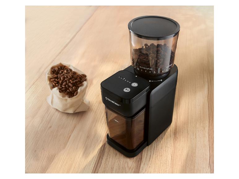 Czarny młynek do kawy SILVERCREST z przezroczystym pojemnikiem na ziarna i workiem ziaren kawy.