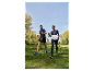 Dwie osoby spacerują po parku z kijami do nordic walking.