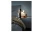 Łóżko z kołdrą, stolik nocny z książką i lampą Philips Hue.